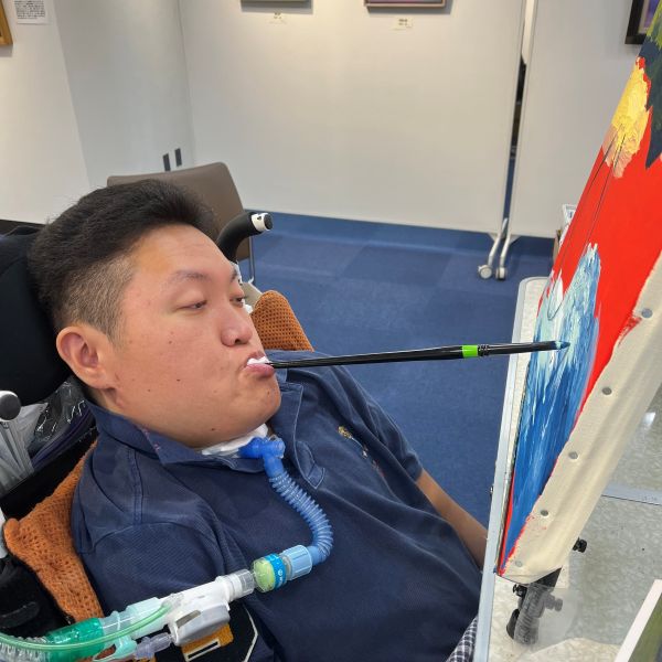 2024年の交通会館展で実演している 田中 潤也（愛媛県／口で描く画家）